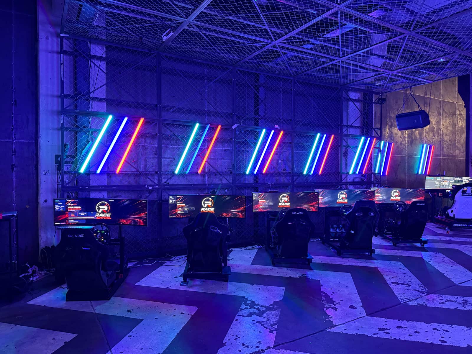 Wide view of the industrial hall with the row of simulators lit by neon tubes