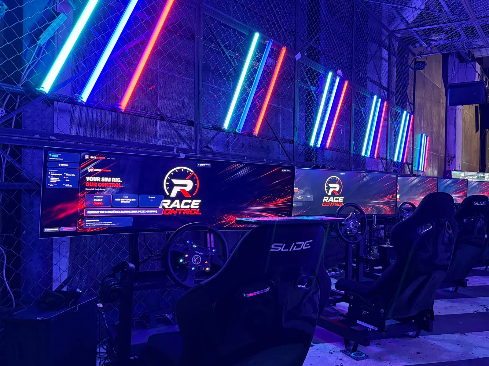 Five simulators lined up under neon tubes at the Gdańsk festival stand, each screen showing the RaceControl idle display