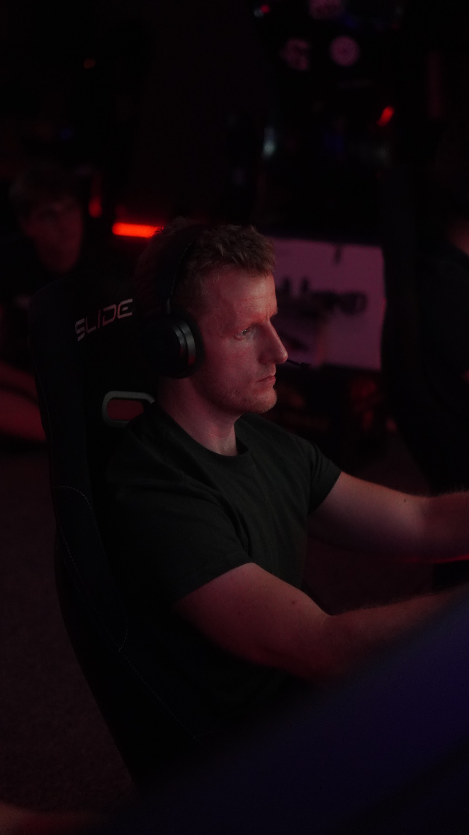 A league driver at the wheel of a simulator, seen from the side during a race