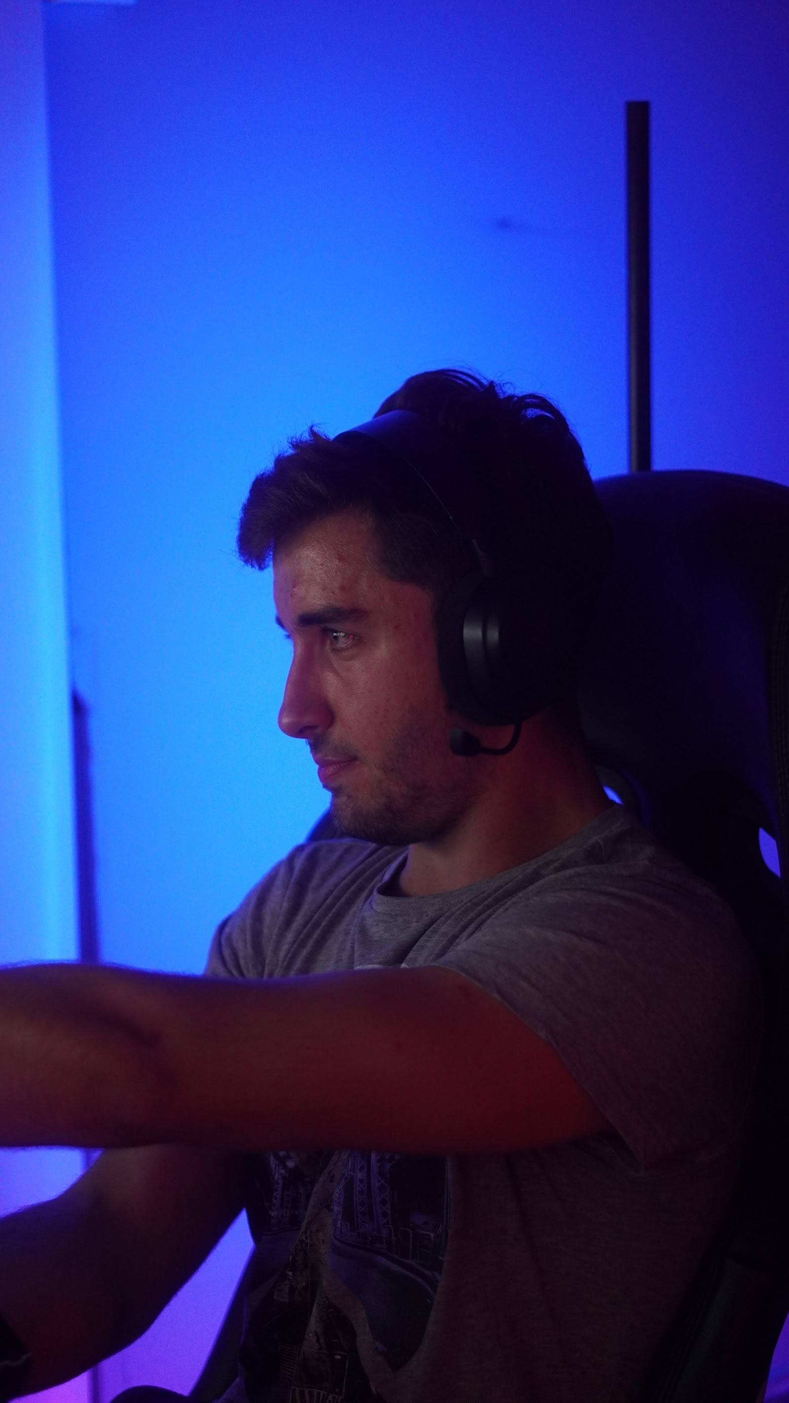 A driver concentrating at the wheel, lit blue by the simulator screens