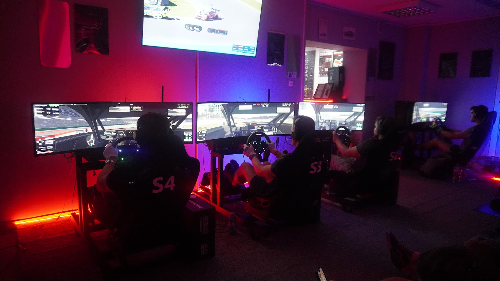The row of simulators lit for the league, drivers seated and racing